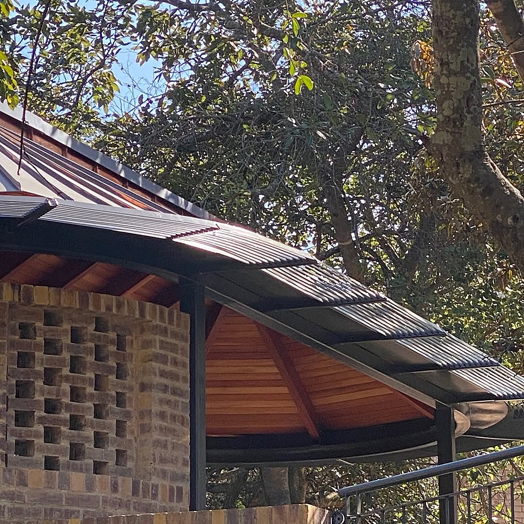 Built pavilion: the copper roof edge over a perforated brick screen wall